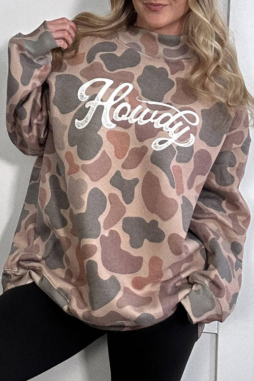 Camouflage-patterned sweatshirt with 'Howdy' text worn by a person against a white background